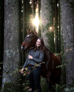 Tess-art Pferdefotografie mit Besitzerin im Wald mit Lichtstrahl im Hintergrund